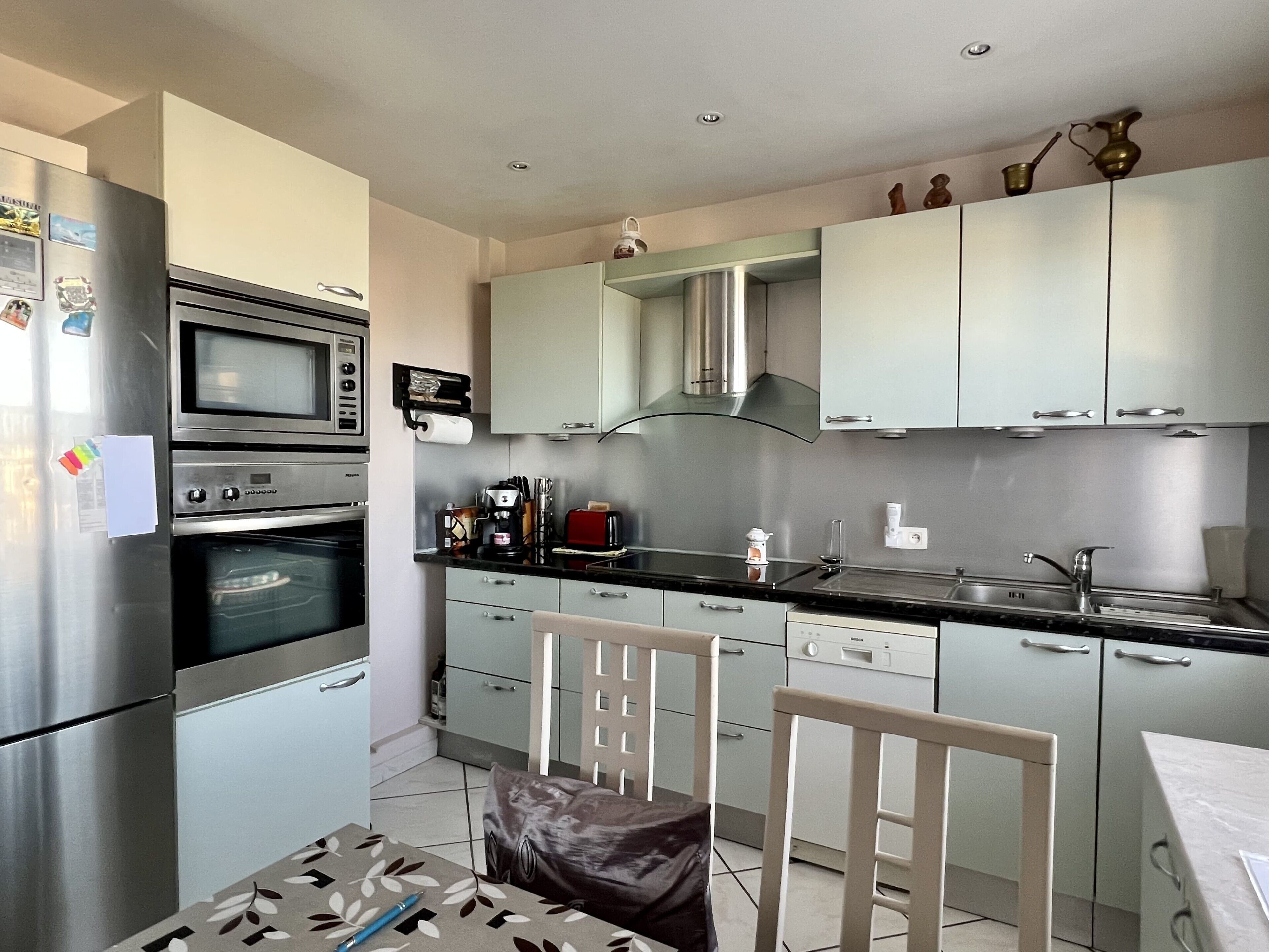 A modern kitchen with stainless steel appliances, a gas stove, and a built-in oven. There is a dining area with a table and chairs.