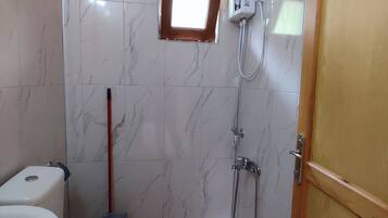 A bathroom with a toilet, a shower, and a small window.