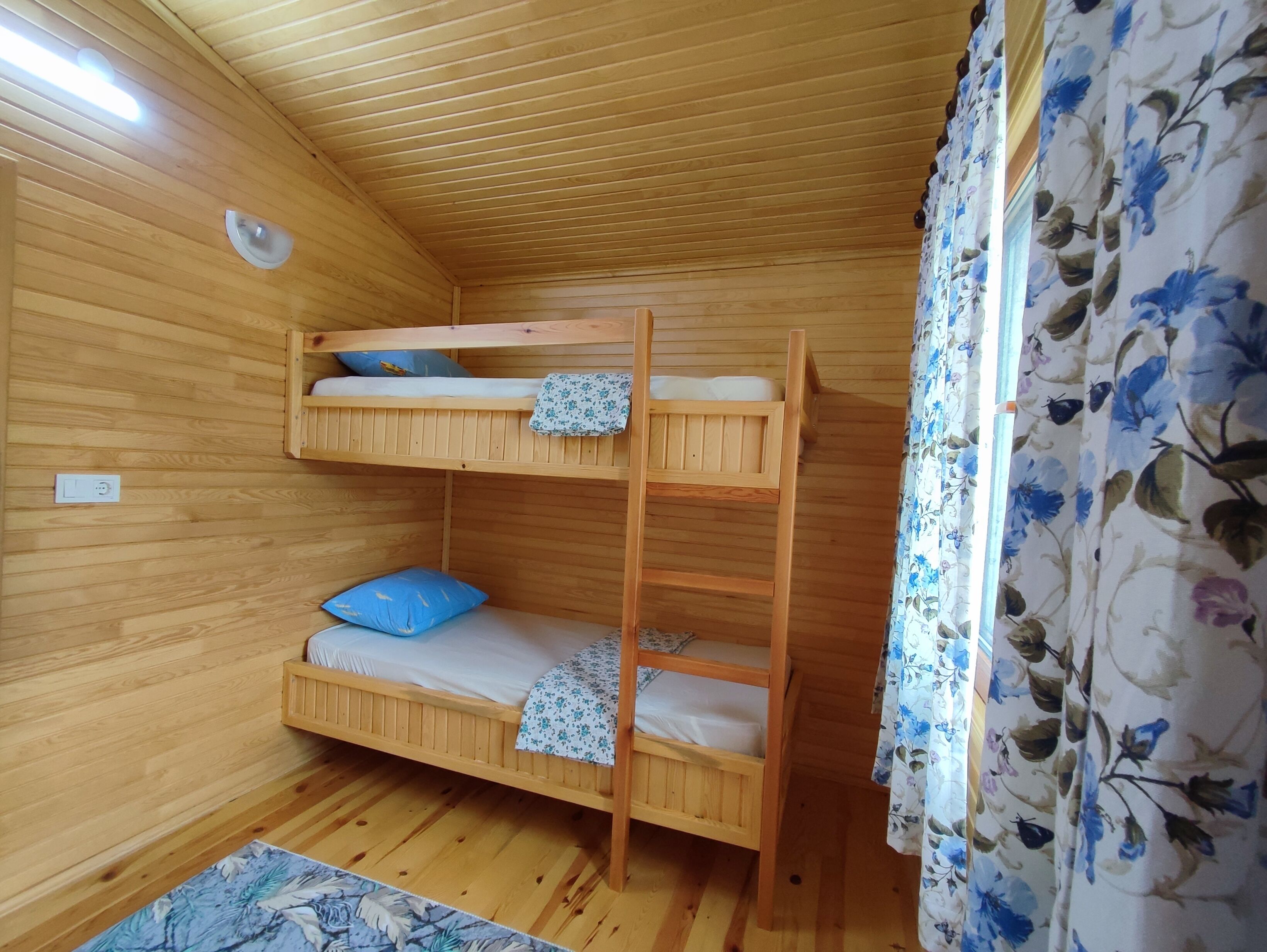 A bunk bed room with wooden walls and a floral curtain.