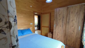 Una habitación con paneles de madera, una cama, un armario y una puerta que da a un espacio exterior.