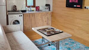 Un espacio habitable compacto con kitchenette, una mesa de comedor, un sofá y un televisor que muestra 'NETFLIX'.