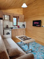 Un espacio habitable compacto con kitchenette, una mesa de comedor, un sofá y un televisor que muestra 'NETFLIX'.