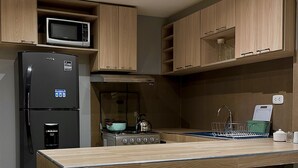 Een moderne keuken met een centraal eiland, barkrukken, een magnetron, een koelkast en een fornuis.