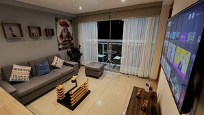 Een moderne woonkamer met een grijze bank, een salontafel en een televisie aan de muur.