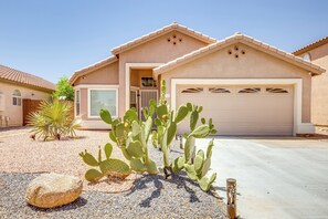 Une maison d’habitation avec un garage, une allée et une végétation de type désertique, notamment des cactus.