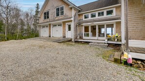 A two-story house with a gravel driveway and a wooden deck. - Waterfront Deer Isle Apartment w/ Fire Pit (Deer Isle)