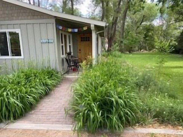 A building with a brick pathway leading to a door, surrounded by lush greenery. - Desert's Edge Fruita (Fruita)