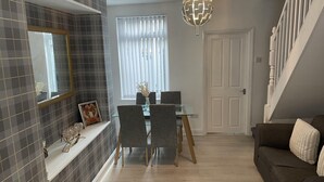 A modern living room with a dining area, a staircase, and a decorative globe light.