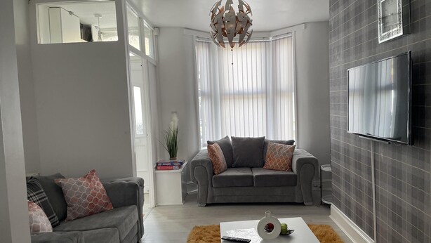 A modern living room with two grey sofas, a white coffee table, and a TV mounted on the wall.