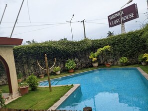 A swimming pool surrounded by potted plants and a sign reading "VERONICA GUEST HOUSE". - Veronica Guest House (Lomé)