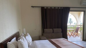 A hotel room with a large bed, a sofa, a balcony with outdoor furniture, and a view of palm trees. - Veronica Guest House (Lomé)