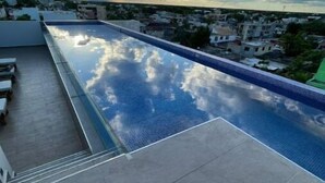 A rooftop pool with a clear view of the surrounding buildings and a cloudy sky.