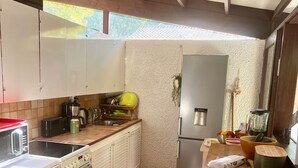 A kitchen with white cabinets, a stove, a refrigerator, and a tiled floor. - La Girolle (Lège-Cap-Ferret)