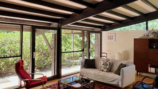 A spacious living room with a large window, a red chair, a white sofa, and a wooden coffee table. - La Girolle (Lège-Cap-Ferret)