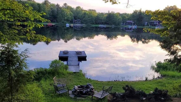 Vistes al llac amb un moll, cadires i una zona de foc.