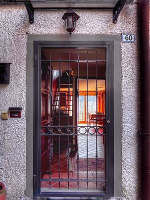 Una porta con cancello in metallo, una cassetta delle lettere e il numero civico 60.