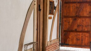 Une porte en bois avec une poignée en métal, une petite fenêtre ornée de vitraux et un mur en briques.
