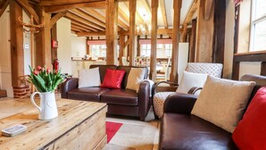 Un salon chaleureux avec des poutres en bois, un canapé en cuir, une table basse et un vase de tulipes.