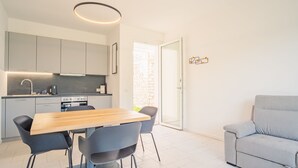 A modern kitchen with grey cabinets, a wooden dining table, and black chairs.