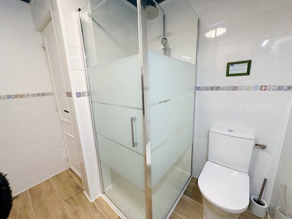 A bathroom with a glass-enclosed shower, a white toilet, and a tiled backsplash.