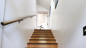 Un escalier en bois, avec des contremarches noires, menant à une porte.