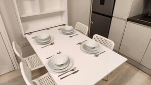 A modern kitchen with white cabinetry, a built-in refrigerator, and a dining table set for four. - Beautiful 2-bed Apartment in London - Sleeps 6! (London)