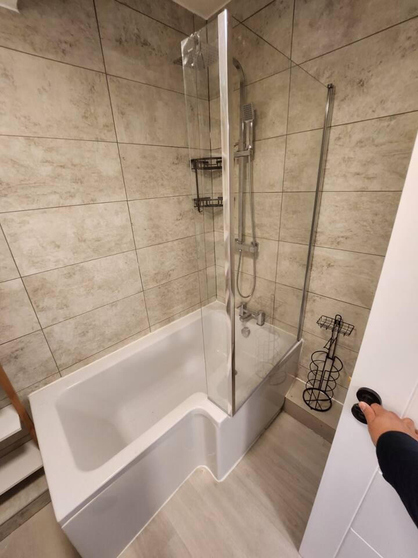 A modern bathroom with a glass-enclosed shower, a white bathtub, and a tiled floor.