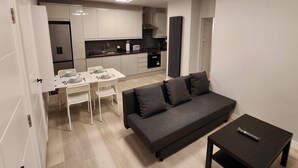 A modern apartment with a dining area, kitchenette, and a living room with a sofa and a coffee table. - Beautiful 2-bed Apartment in London - Sleeps 6! (London)