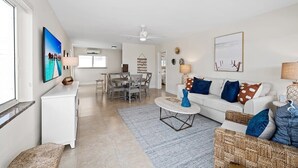 A spacious living room with a white sofa, a coffee table, and a dining area with a table and chairs. - Bermuda Isles Villas - King #29 (Lauderdale-by-the-Sea)