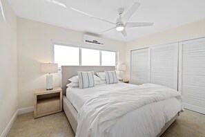 Un dormitorio con cama, mesitas de noche, ventilador de techo y ventana.