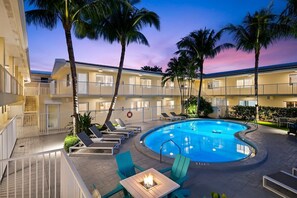 Un hôtel doté d’une piscine, de chaises longues et d’un foyer extérieur.