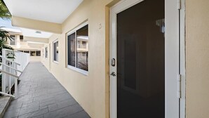 Ein Flur mit einer geschlossenen Tür, einem Fenster und einem Balkon mit Geländer.