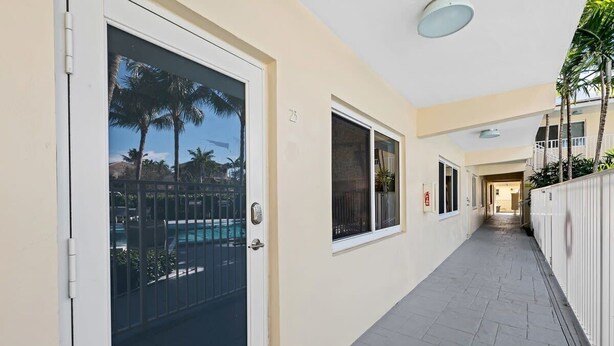 A corridor with a pool view, a door, and a window. - Bermuda Isles Villas - King #23 (Lauderdale-by-the-Sea)