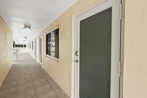 A corridor with doors, a ceiling fan, and a tiled floor.