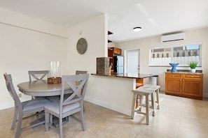 Una cocina moderna con una isla central, armarios de madera y un área de comedor con sillas grises.