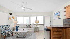Ein modernes Wohnzimmer mit Sofa, Sessel, Couchtisch und Deckenventilator.