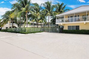 A hotel with a two-story structure, a covered outdoor area, and palm trees.