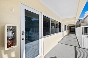 Un couloir avec une porte vitrée, un extincteur et un balcon doté d’une rambarde.