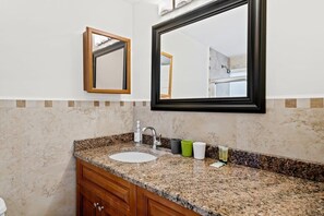 A bathroom with a granite countertop sink, a mirror, and a wooden cabinet.