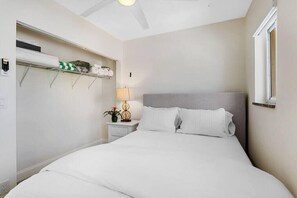 Une chambre à coucher avec un lit, une table de chevet, une lampe et une étagère avec divers objets.