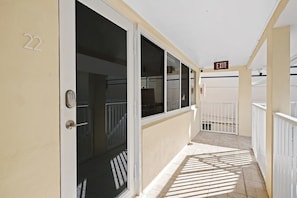 A hotel corridor with an exit sign, a door with a keypad, and a number '22' on the wall.