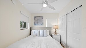 Una camera da letto con un letto, un comodino, una lampada, una ventola a soffitto e un armadio.