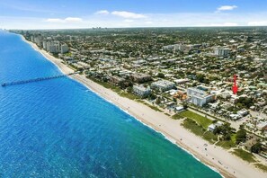 Vista aerea di una città costiera con spiaggia, molo e fitto sviluppo urbano.