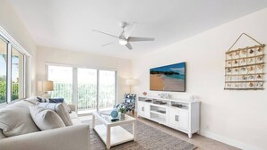 Un salon moderne avec un canapé, une table basse, un téléviseur et une étagère fixée au mur.