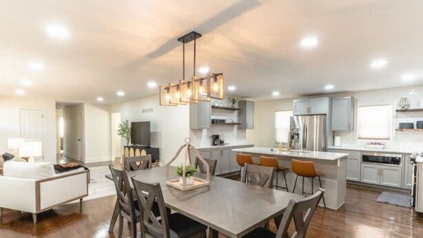 A modern kitchen with white cabinets, a central island, and a dining area with a wooden table and chairs.
