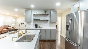 A modern kitchen with a stainless steel refrigerator, white cabinetry, and a central island with a sink.