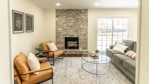 A living room with a stone fireplace, two sofas, a coffee table, and a large window.