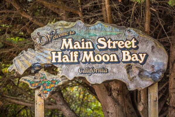 A rustic wooden sign with the text "Welcome to Main Street Half Moon Bay, California."