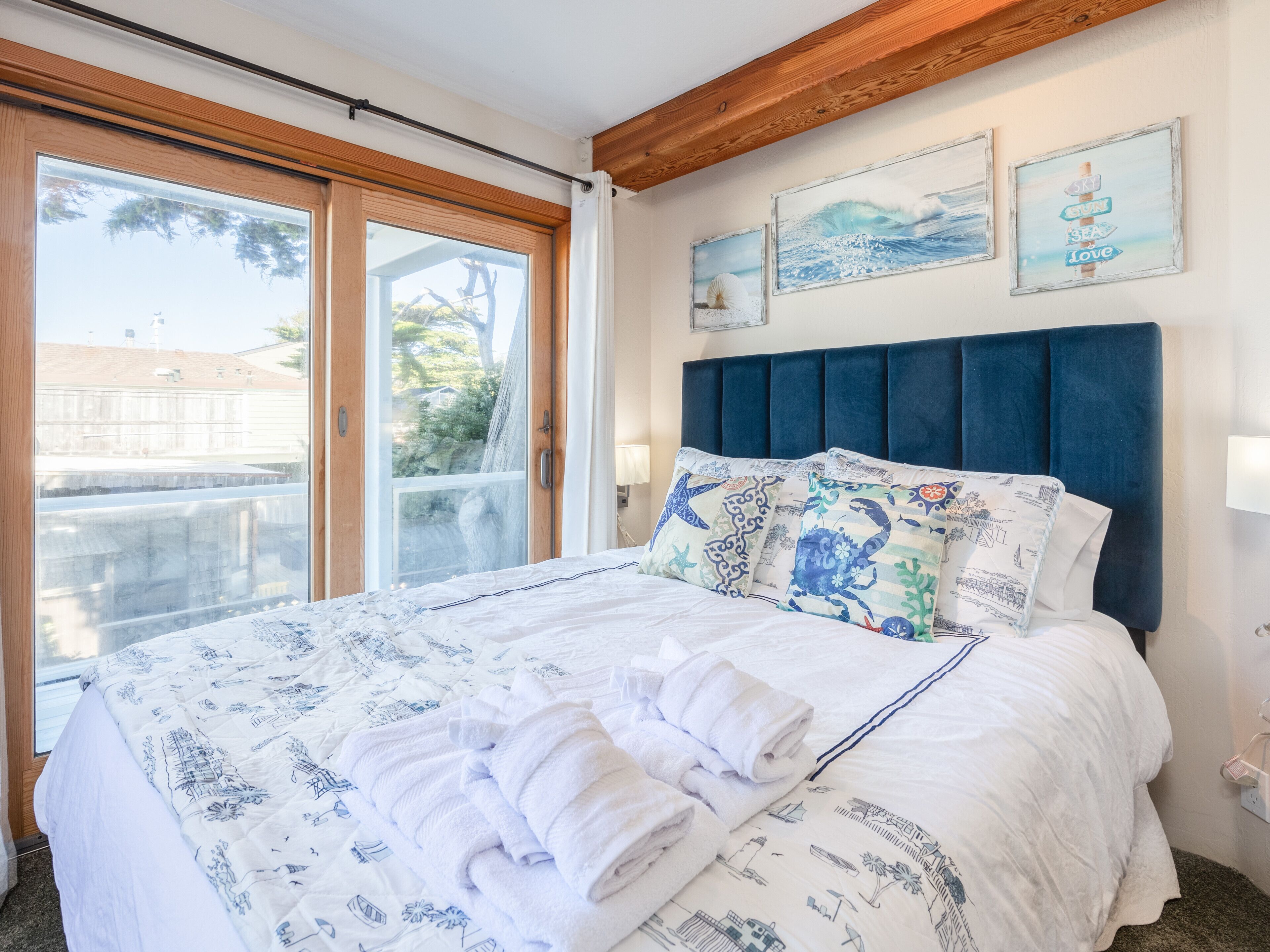 Quarto com uma cama grande, teto de madeira e vista para o exterior por uma porta de correr de vidro.