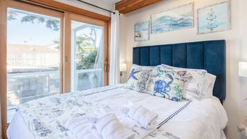 Quarto com uma cama grande, teto de madeira e vista para o exterior por uma porta de correr de vidro.